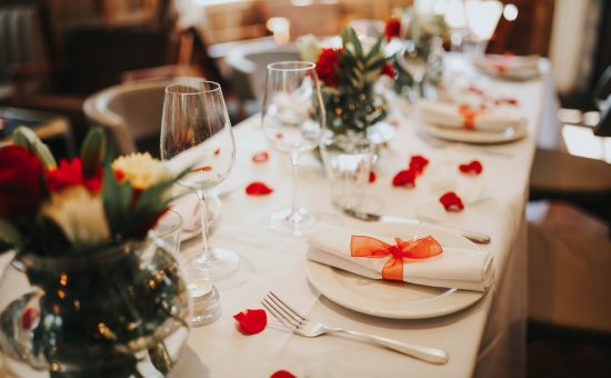 Wedding table setting decorated with fresh flowers and silverware. Concept of fine dining, catering and exclusive private hire of an event space. Banquet table set up for a wedding reception or dinner