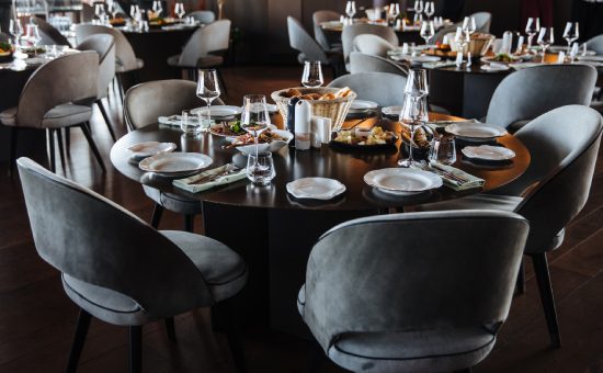 Beautifully organized event - round served table banquet ready for guests, round decorated table with empty plate, glasses, forks, napkin. Elegant dinner table