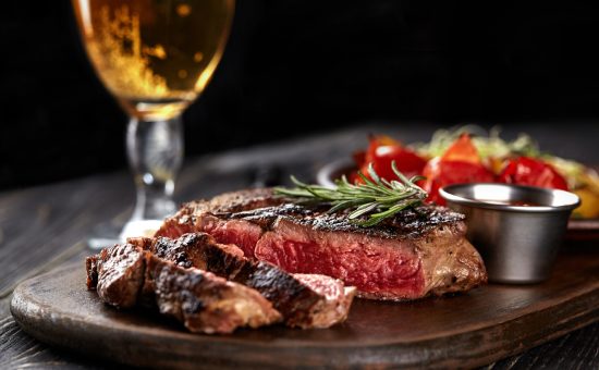 Juicy steak medium rare beef with spices on wooden board on table