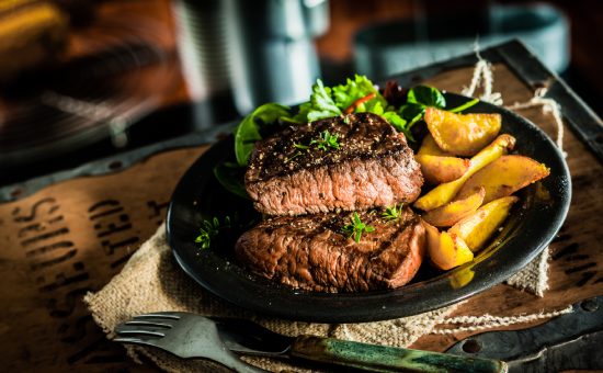 Healthy lean grilled medium-rare beef steak and vegetables with roasted pumpkin and a leafy green herb salad in a rustic pub or tavern