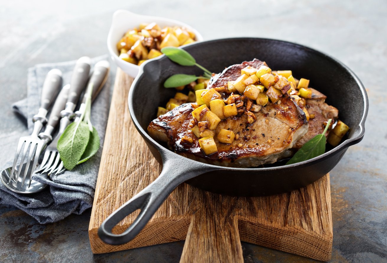 Sauteed pork chops with caramelized apples and walnuts in a cast iron pan
