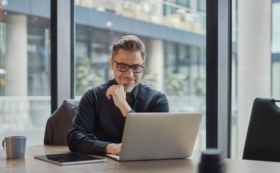 Businessman using laptop computer in office. Happy middle aged man, entrepreneur, small business owner working online.