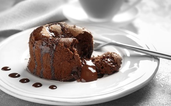 Plate of delicious fresh fondant with hot chocolate on table. Lava cake recipe