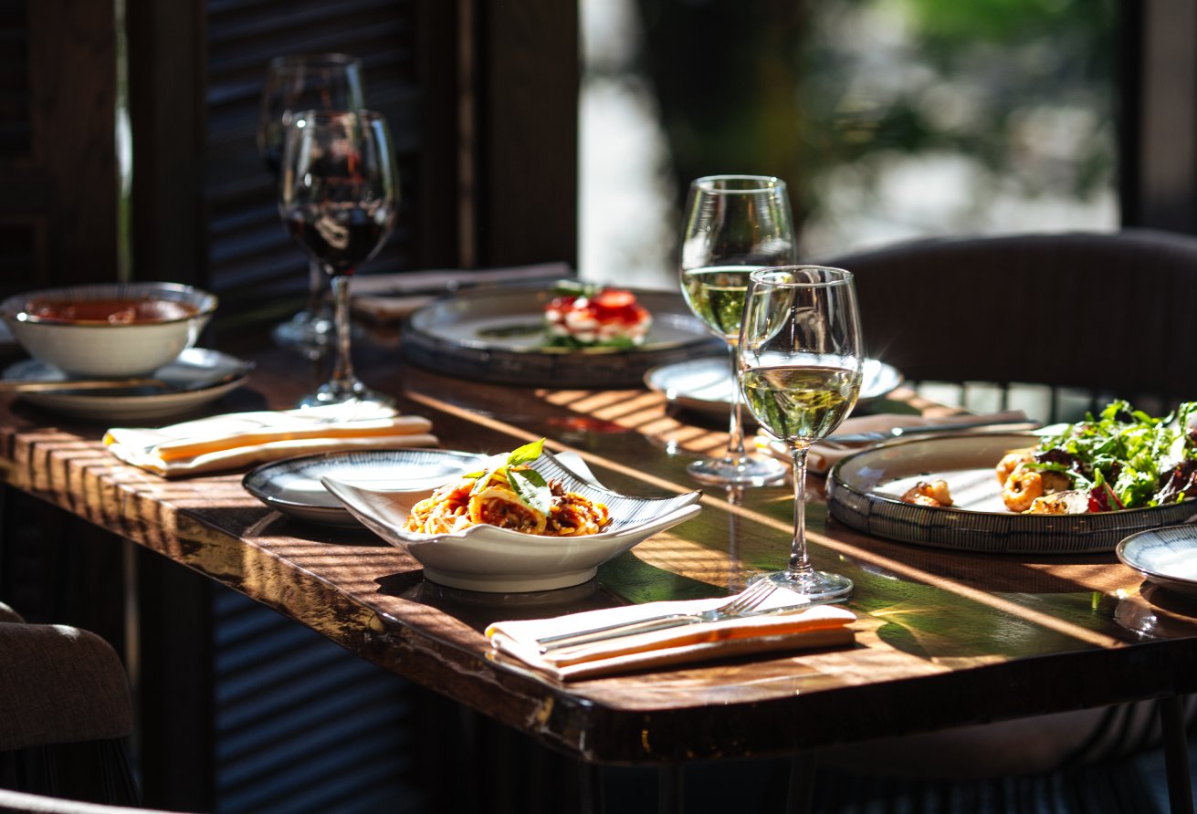 Served table with italian food - seafood pasta, salad and wine with window light